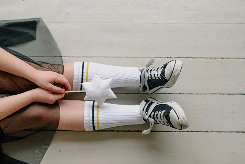 White crew socks with stripes paired with sneakers, demonstrating mid-calf sock height for comfort and style.